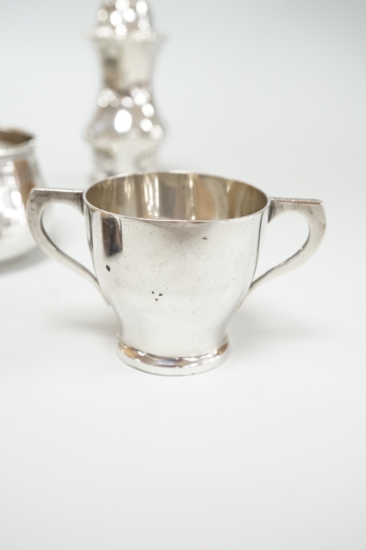Four assorted silver condiments including a Victorian bun salt and a late Victorian pepper mill, together with a small silver bowl, a silver matchbox sleeve and a small silver two handled cup.